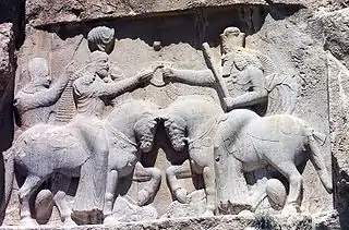 Investidura de Ardacher I (fundador de la dinastía sasánida, en el siglo&nbsp;III) por el dios Ahura Mazda. Sus caballos pisotean al anterior rey, Artabán&nbsp;IV, y a la deidad negativa Ahriman. Naqsh i Rustam.